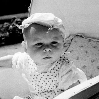 Baby in vintage stroller with hat.