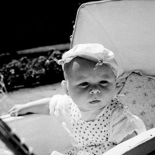 Baby in vintage stroller with hat.