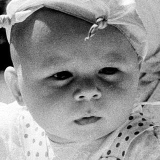 Baby in vintage stroller with hat.