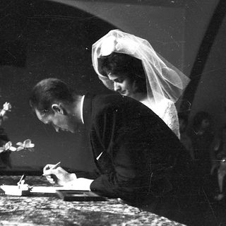 Wedding couple signing guest book indoors.