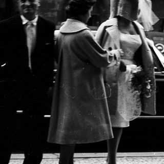 Wedding couple exiting vintage car with attendants.