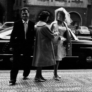 Wedding couple exiting vintage car with attendants.