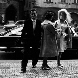 Wedding couple exiting vintage car with attendants.