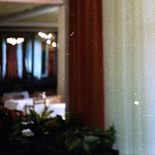 Man in light shirt looking at phone indoors.