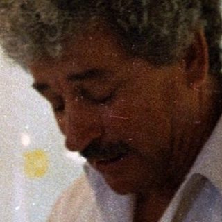 Man in light shirt looking at phone indoors.
