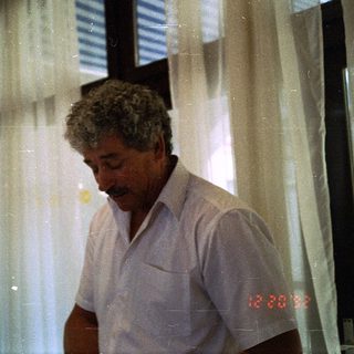 Man in light shirt looking at phone indoors.