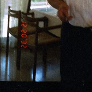 Man standing indoors near window holding remote control.