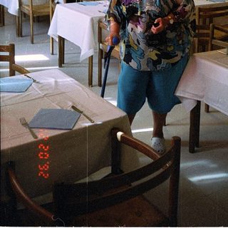 Woman smiling indoors in a restaurant with set tables.