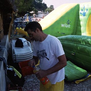 Man drinking near inflatable water toys.
