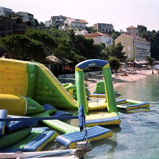 Waterfront beach with inflatable slides and sea activities.