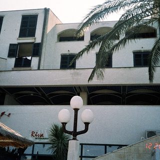 Modern building with restaurant "Riva" and outdoor seating.