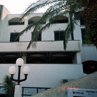 Modern building with restaurant "Riva" and outdoor seating.