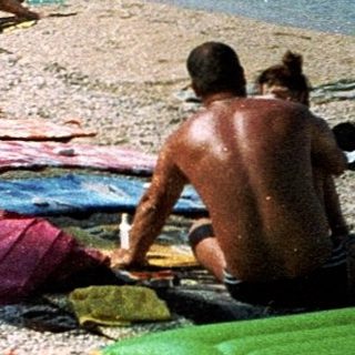 Sunny beach with people relaxing by the sea.