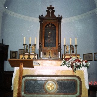Religious altar with crucifix, candles, and religious artwork.
