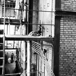 Industrial factory with workers on elevated platforms.
