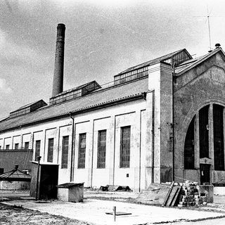 Industrial building with large arched entrance and smokestack.