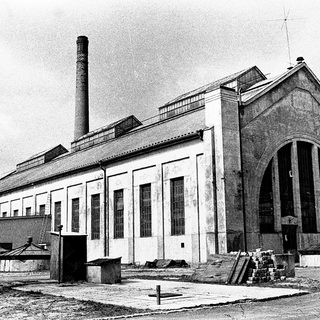 Industrial building with large arched entrance and chimney.