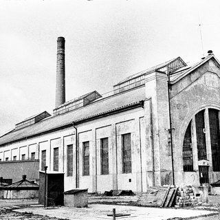 Industrial building with large arched entrance and chimney.