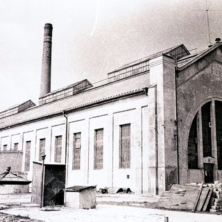 Industrial building with large chimney, arched entrance.