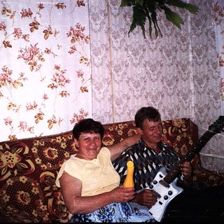 Two people playing guitar and singing together indoors.