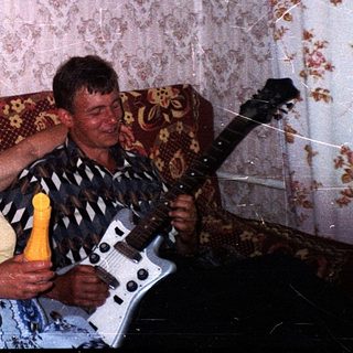 Two people playing guitar and singing together indoors.