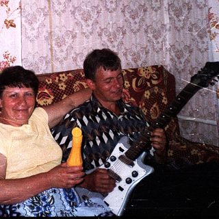 Two people playing guitar and singing together indoors.
