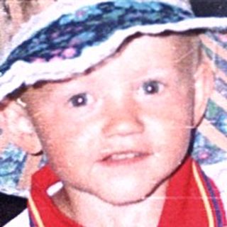Child wearing wide-brimmed hat and colorful shirt.