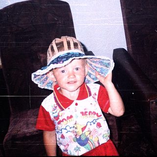 Child wearing wide-brimmed hat and colorful shirt.