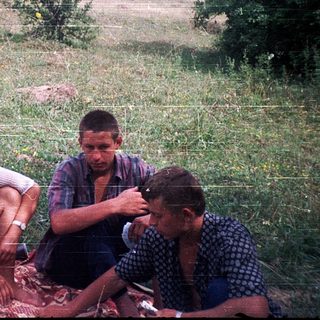Four people sitting outdoors in rural field.