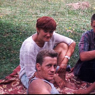 Four people sitting outdoors in rural field.