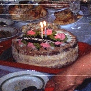 Family celebrating birthday with cake indoors.