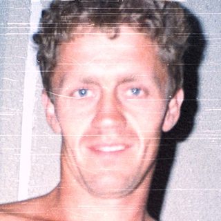 Shirtless man holding a white object indoors.