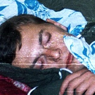 Person sleeping on bunk bed in rustic room.