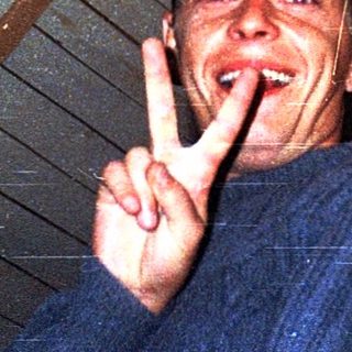 Man making peace sign indoors under slanted roof.