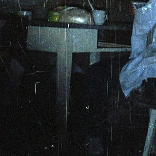 Person sitting indoors under rain shower curtain.