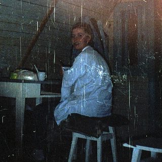 Person sitting indoors under rain shower curtain.
