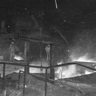 "Black-and-white nighttime photo of a damaged building under meteor shower."