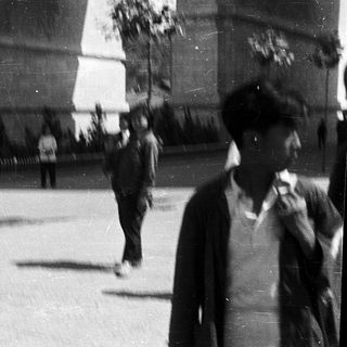 Blurred street scene with pedestrians in mid-20th century clothing.
