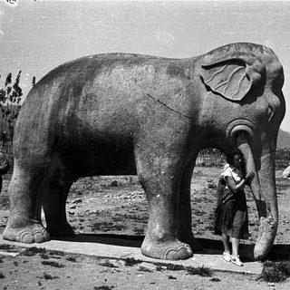 Large statue of an elephant with a child touching its trunk.