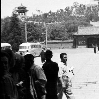 Historic Beijing courtyard with traditional architecture and pedestrians.