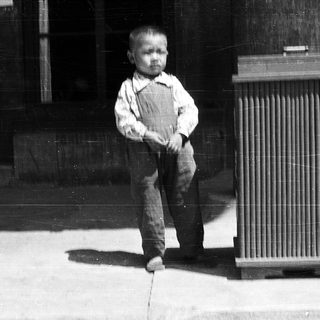 Young boy standing outdoors near building.
