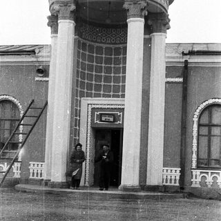 Historic building entrance with two men standing.