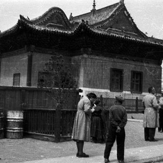 Traditional East Asian building with people outside in vintage clothing.
