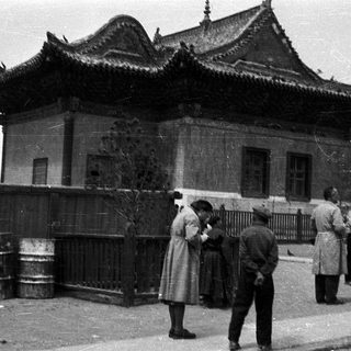 Traditional East Asian building with people outside in vintage clothing.