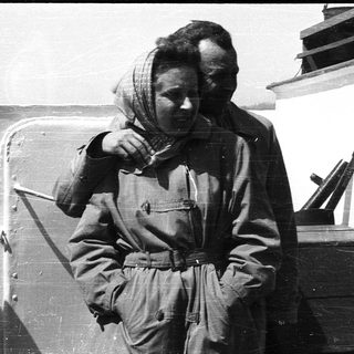 Woman in military uniform adjusting scarf on ship.