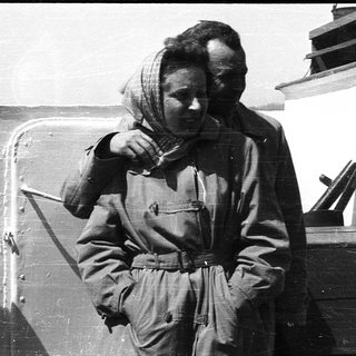 Woman in military uniform adjusting scarf on ship.