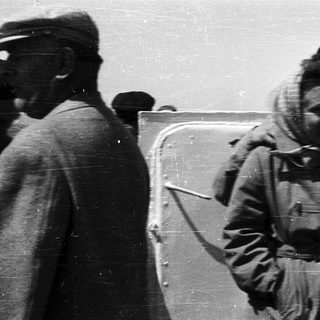 People in heavy winter clothing near a vehicle.