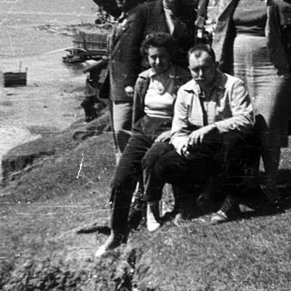 Group of people posing outdoors by coastal cliffs.