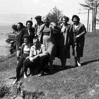 Group of people posing outdoors by coastal cliffs.