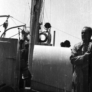 Man standing near vintage naval ship equipment.